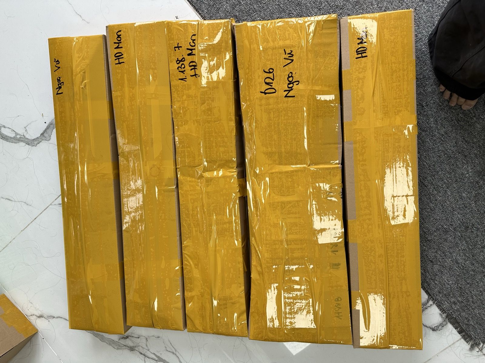 Five sealed parcels wrapped in yellow tape with handwritten notes, ready to ship