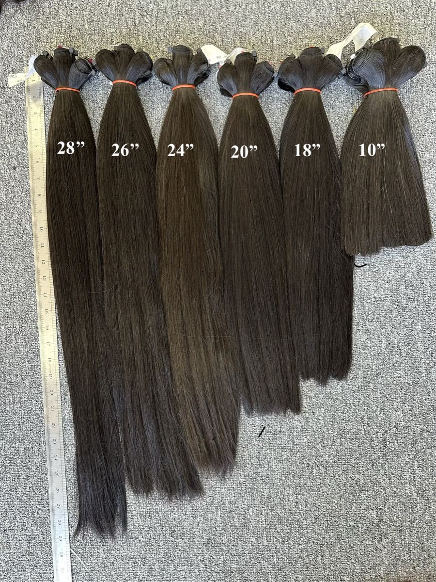 Six tied bundles of straight dark hair from 28 down to 10 inches next to a measuring tape