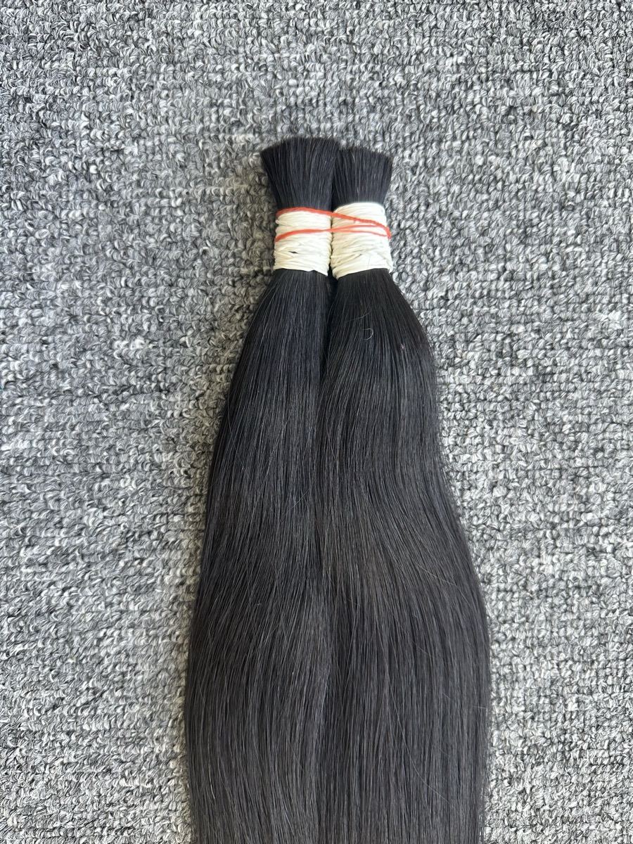 Close view of two tied bunches of straight dark bulk hair on a carpet